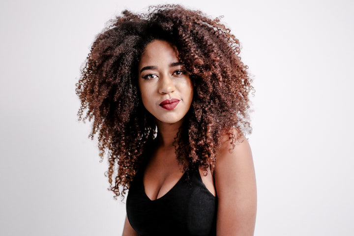 Woman with big, curly-coily hair with red lipstick wearing a black top