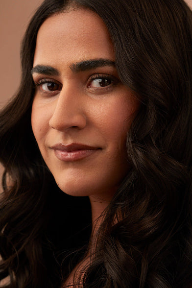 Close-up of a woman with long, dark hair against a neutral background